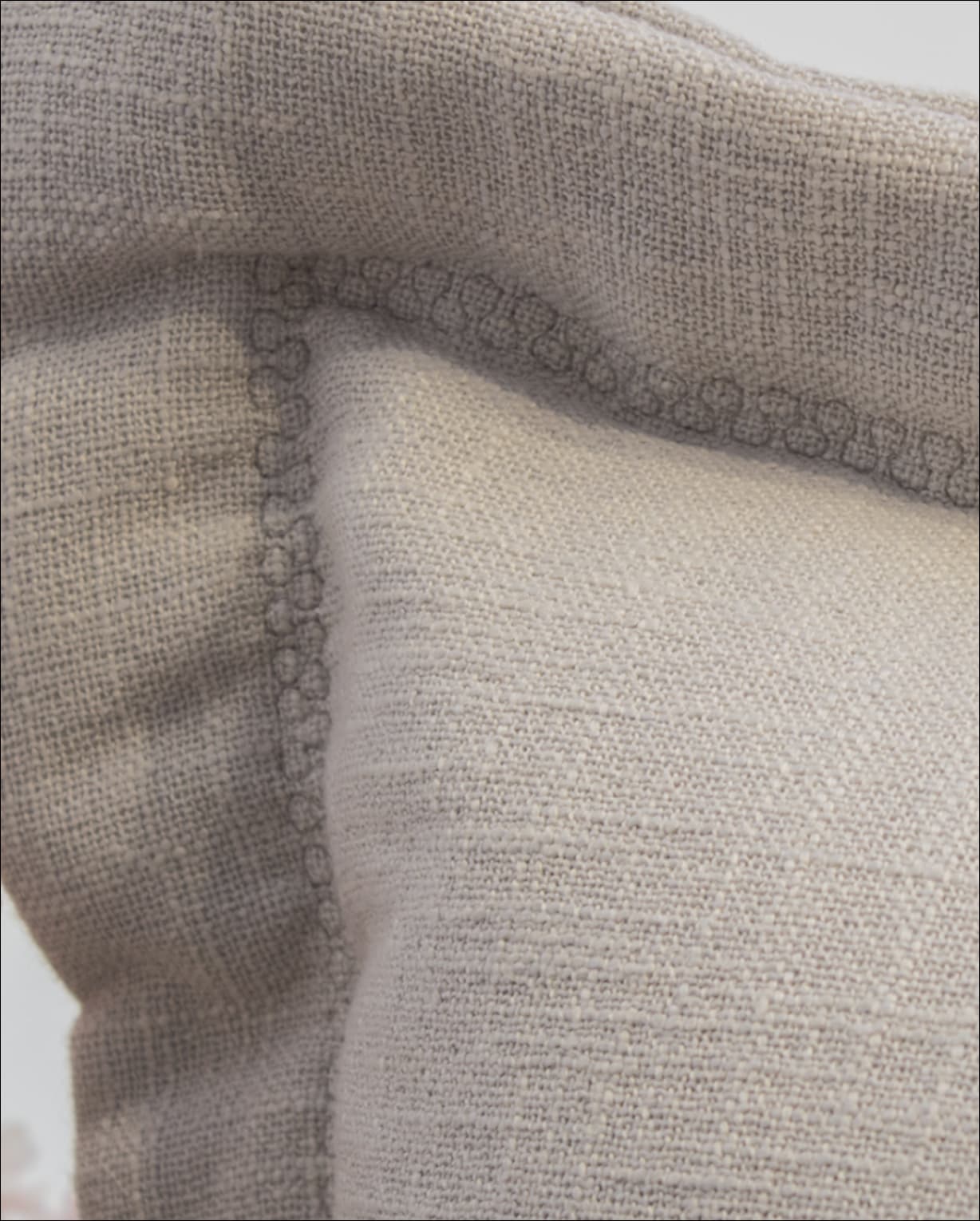 Detail of artisanal stitching on a linen cushion